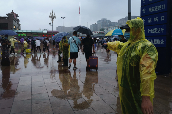 北京站地区工作人员在广场引导旅客通行